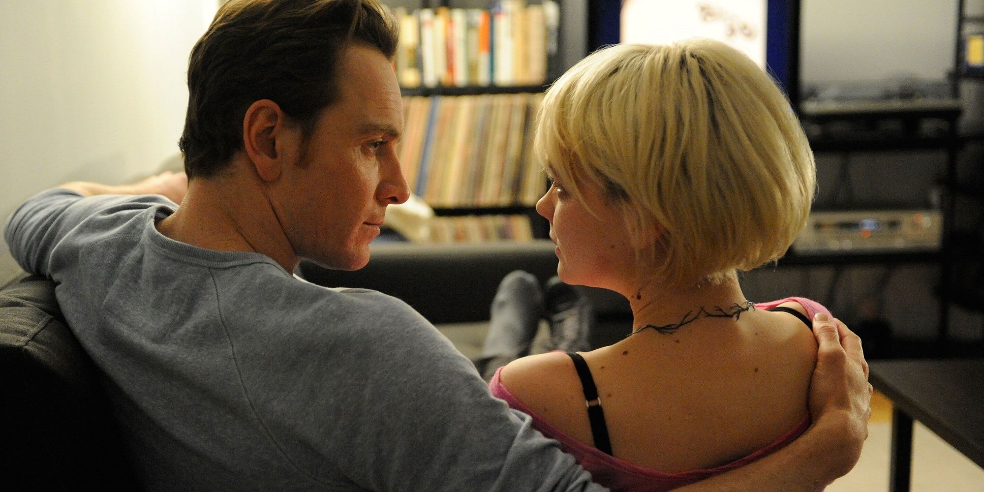 Michael Fassbender as Brandon and Carey Mulligan as Sissy sit on a couch and look at each other in 'Shame.'
