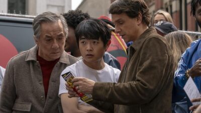 Mr. Han, Li, and Daniel looking at a pamphlet in Karate Kid: Legends
