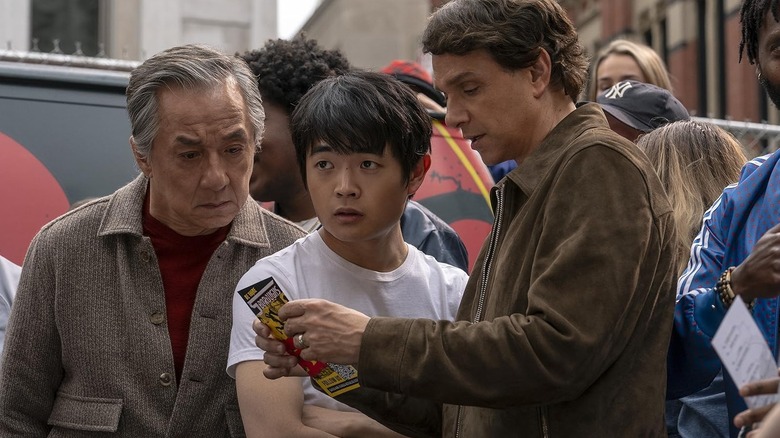 Mr. Han, Li, and Daniel looking at a pamphlet in Karate Kid: Legends